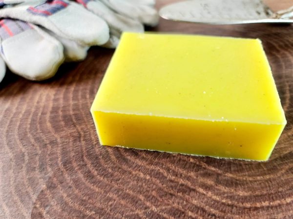 A picture of yellow soap next to gardening tools.