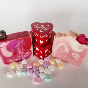 A picture of two Valentine's Day Soaps, one with dark red and pink swirls, one with pink and cream swirls. Both have hearts imbedded on top.