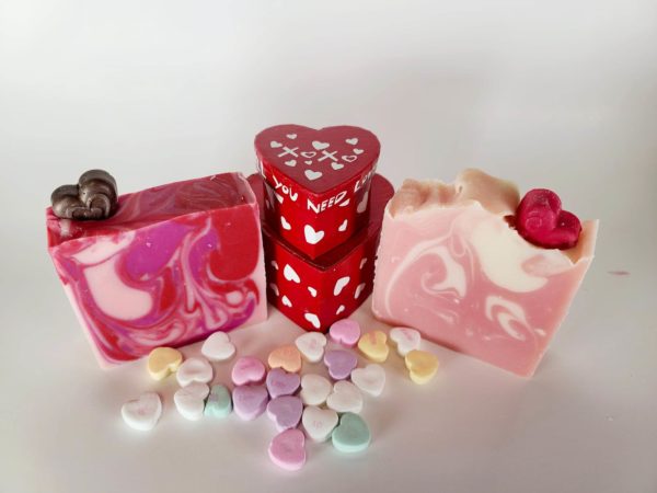 A picture of two Valentine's Day Soaps, one with dark red and pink swirls, one with pink and cream swirls. Both have hearts imbedded on top.