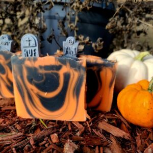 A picture of three black and orange swirled soaps, each with a gray-colored tombstone imbedded to their top.