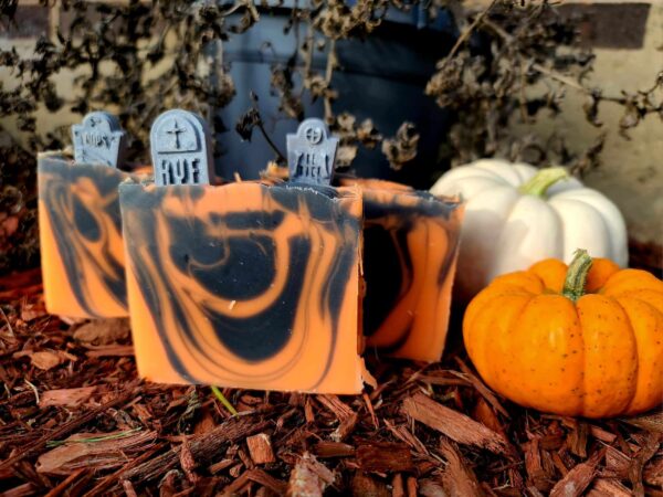 A picture of three black and orange swirled soaps, each with a gray-colored tombstone imbedded to their top.