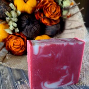 A red and white swirled bar of soap set in front of an arrangement of brown, red, and yellow Fall flowers.