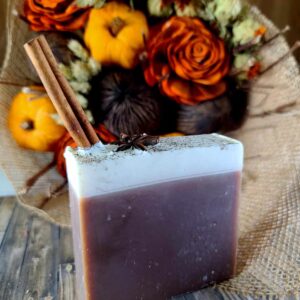 A picture of a bar of soap resembling hot apple cider, brown on the bottom with white on top and possessing Cinnamon Stick and Star Anise imbeds.