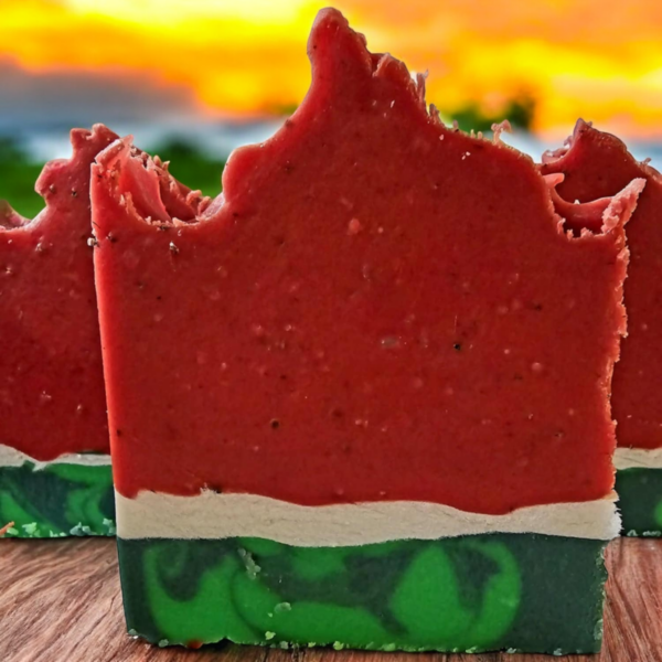 Three soaps that look like Watermelons on a beach at sunset.