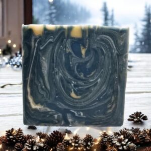 A gold, blue-green, and white swirled bar of soap sitting on a Christmas-decorated kitchen table in front of a window looking out on an alpine winter storm.