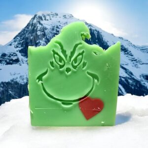 A green soap with a red heart embed with teh face of Dr. Seuss's The Grinch stamped on it.